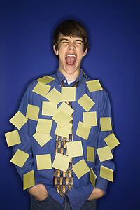 Portrait of Caucasian teen boy covered with sticky notes and screaming.