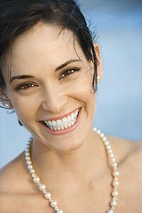 Portait of Caucasian mid-adult woman in pearls smiling and looking at viewer.