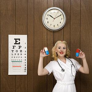 Caucasian mid-adult female nurse standing by wood paneling holding oversized pills and smiling at viewer.
