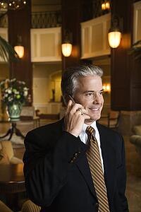 Caucasian prime adult male businessman talking on cellphone in hotel lobby.