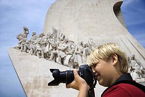 Caucasian boy looking through camera at the Monument to the Discoveries in Lisbon, Portugal.