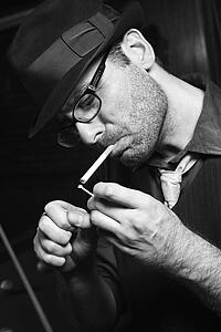Caucasian prime adult retro male lighting cigarette.