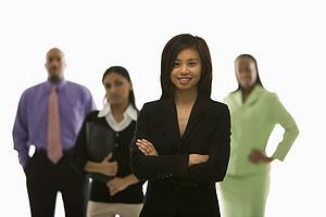 Portrait of Vietnamese businesswoman smiling with arms crossed with others in background.