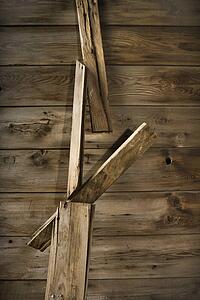 Close up of side of rustic wooden building with wood pieces hanging down.