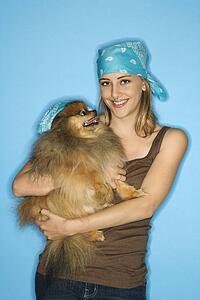 Caucasian teen female holding Pomeranian dog.