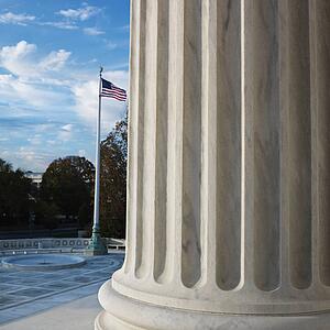 Column of Supreme Court building with American flag in Washington D. C.