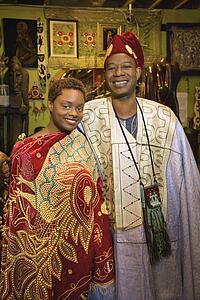 Portrait of smiling mid-adult African-American man and his young adult daughter wearing traditional African clothing.