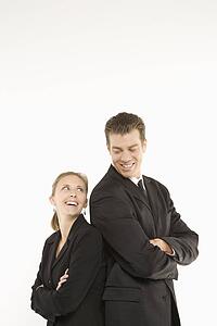 Caucasian mid-adult businessman and woman standing back to back and smiling at each other. 