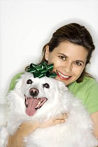 Caucasian prime adult female holding fluffy white dog.