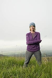 Middle-aged Caucasian woman standing alone in field.