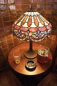 High angle still life of table with beer glass, pitcher, and cigarette ashtray in nightclub.