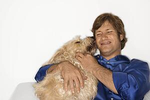 Male Caucasian young adult with fluffy brown dog.
