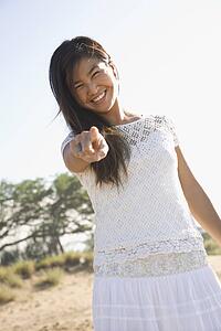 Young adult Asian female pointing at viewer.