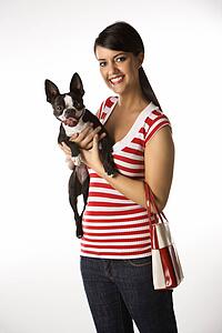 Young adult female Caucasian holding Boston Terrier dog.