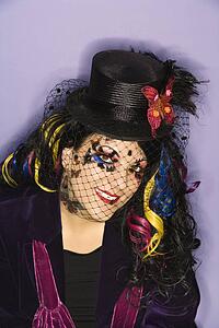 Portrait of Caucasian woman in unique makeup and clothing against purple background.