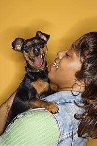 African American young adult female holding Miniature Pinscher dog.