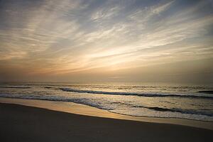 Ocean waves lapping on the shore at sunset.