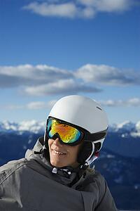 Caucasian teenage boy snowboarder wearing helmet and goggles on mountain.