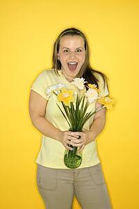 Young adult female Caucasian standing holding flowers.