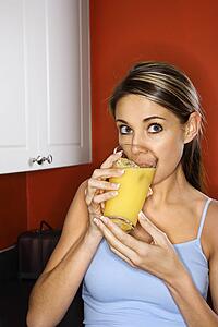 Portrait of young adult woman drinking a glass of orange juice.