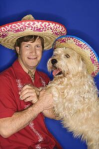 Fluffy brown dog and Caucasian male young adult wearing Mexican sombreros.