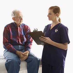 Mid-adult Caucasian female in scrubs taking notes from elderly Caucasian male.