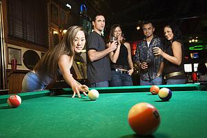 Young asian woman preparing to hit pool ball while playing billiards.