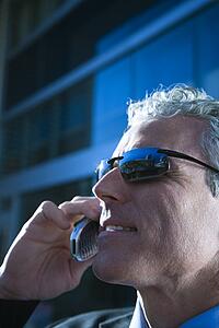 Close up side view of prime adult Caucasian man in suit talking on cellphone in urban setting.