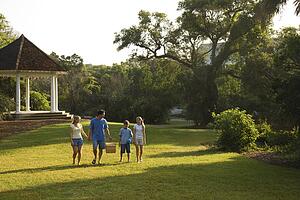 Caucasian family of four walking in park carrying picnic basket.