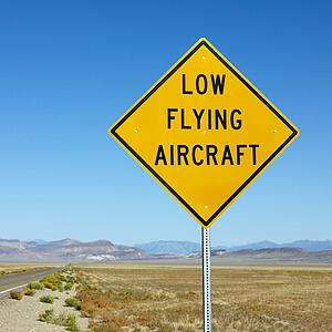 Low flying aircraft sign alongside desolate highway.