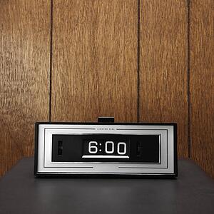Retro clock set for 6: 00 against wood paneling.