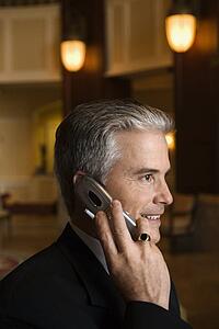 Caucasian prime adult male businessman talking on cellphone in hotel lobby.