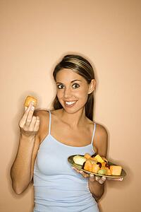 Portrait of young adult woman holding up a piece of fruit. 