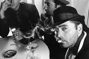 Three Caucasian prime adult males in retro suits sitting at table drinking cocktails.
