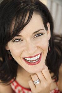 Mid-adult Caucasian woman smiling wearing wedding ring.