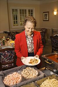 Elderly Caucasian woman at buffet in the dining room of a retirement community center.