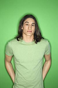 Portrait of Asian-American teen boy standing against green background.