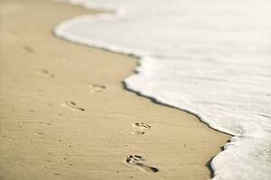Scenic sandy coastline with footprints and waves.