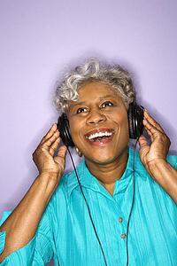 Mature adult African American female listening to headphones.