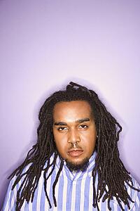 Serious African-American mid-adult man on purple background.