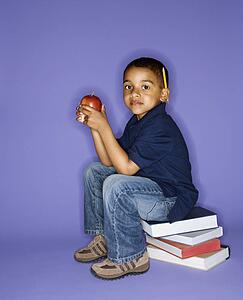 African American male child sitting on stack of books.
