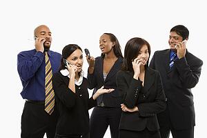 Multi-ethnic business group of men and women standing talking on cell phones.