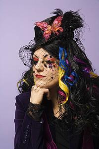 Portrait of Caucasian woman in unique makeup and clothing against purple background.