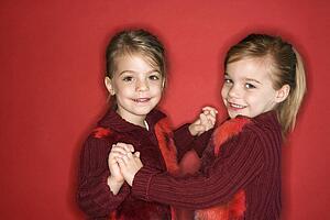 Female children Caucasian twins standing in dance stance.