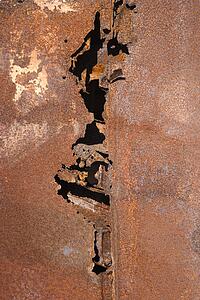Close-up of old rusted car with crack down the middle.