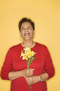 African American mature adult female holding flowers.