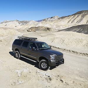 Four wheel drive truck on dirt road in barren landscape in Death Valley National Park.