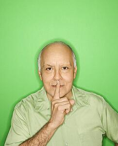 Caucasian mature adult male holding finger to mouth.