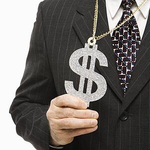 Close-up of Caucasian middle-aged businessman wearing chain necklace with oversized dollar sign.