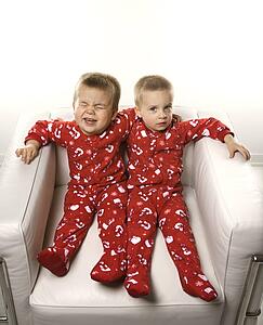 Caucasian male twin children sitting together on chair.